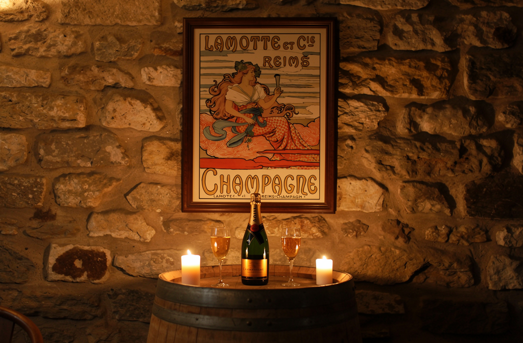 Table ronde en tonneau avec bouteille de champagne et deux verres, éclairage de bougies, œuvre d’art lithographiée au mur en pierre. Alt: lithographie procédé, mais ensure keyword integrated: "lithographie procédé" within description. Let's craft French sentence <125 chars. Proposition: "Table ronde sur barrique avec bouteille de champagne et verres, éclairée par des bougies; lithographie procédé affichée sur le mur en pierre." Count chars roughly. Good. Let's output final. Ensure not too long. Include keyword: "lithographie procédé" as continuous phrase. Use: "Affiche lithographie procédé sur le mur." But it's "lithographie procédé" exact. We'll include: "Affiche lithographie procédé sur le mur." Good. Final string: "Table ronde sur barrique avec bouteille de champagne et verres, éclairée par des bougies; affiche lithographie procédé sur le mur en pierre." <= fits. Let's output.
